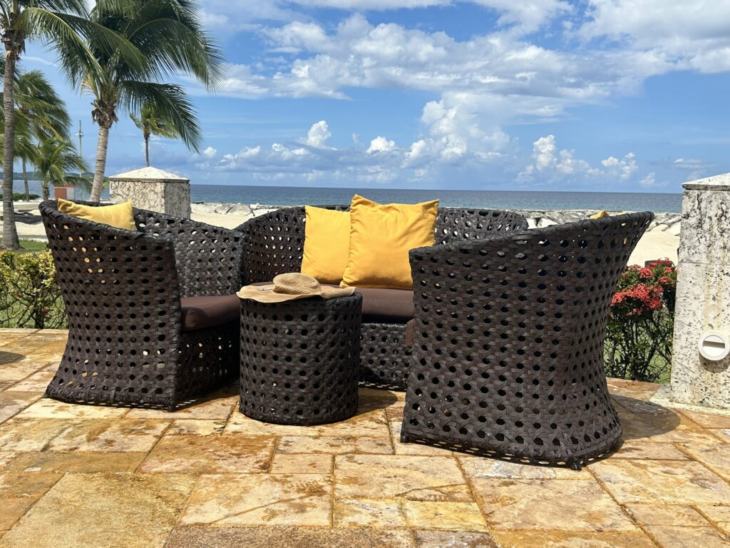 Beach chairs & little table by the beach overlooking the ocean.