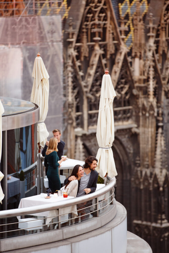 Two couples having dinner on a balcony overlooking Vienna