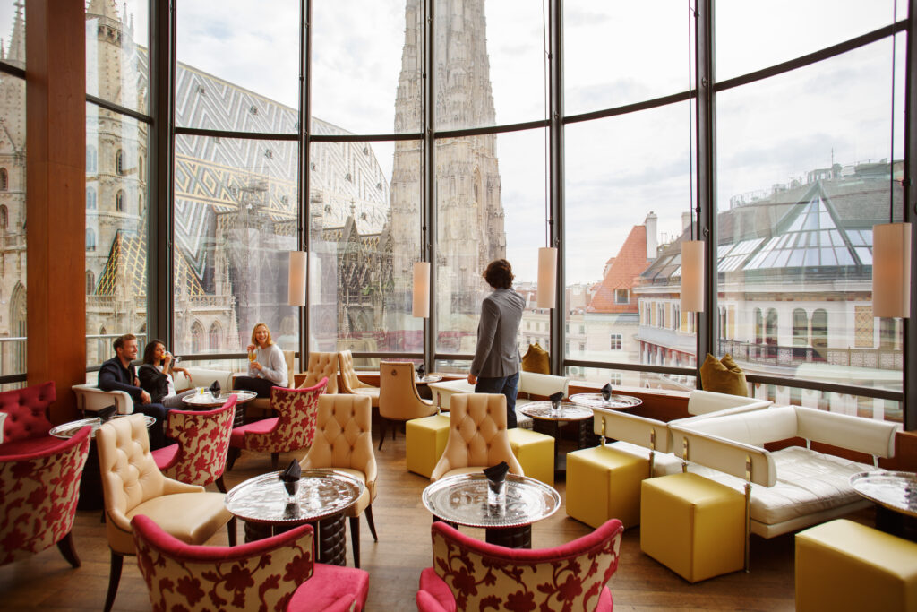 A Vienna cafe with people drinking coffee looking out large windows looking out at Vienna.