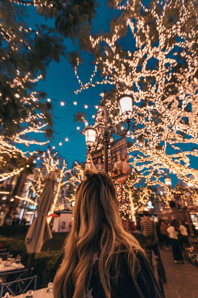 A holiday scene with magical Christmas lights and a lady looking at them.