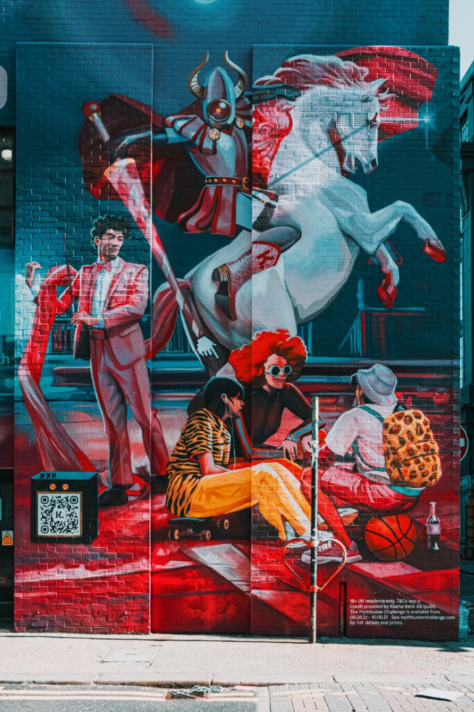 A cool mural in Shoreditch with a a prancing white horse, a guy in a red suit and three people having a powpow at the front.