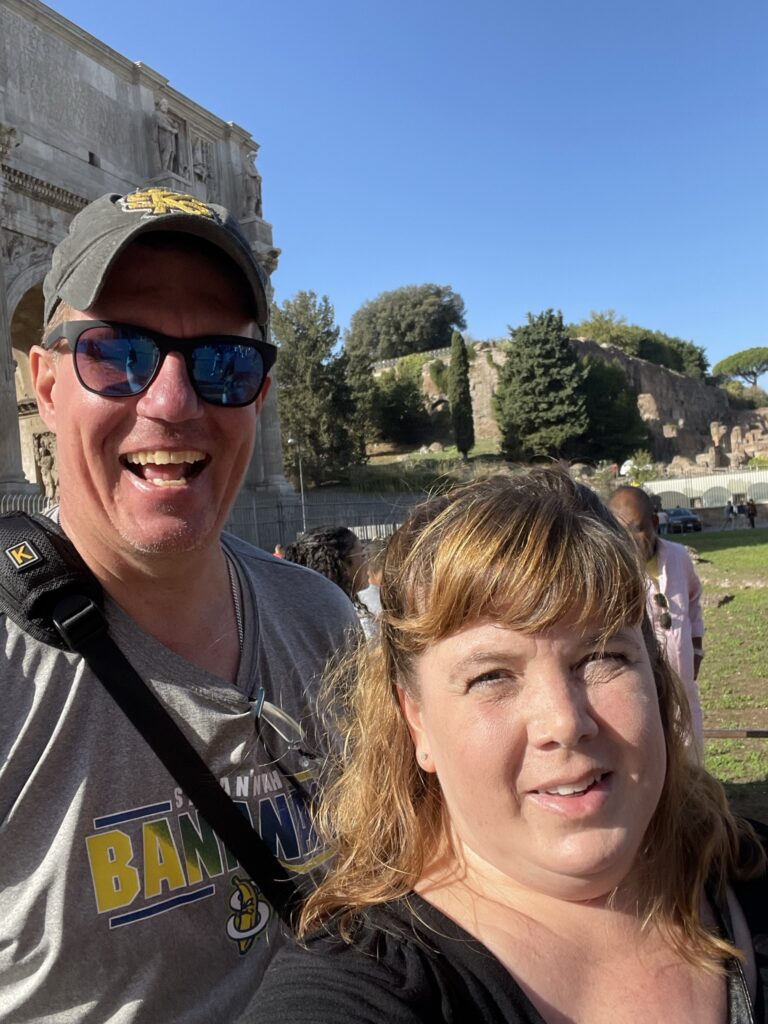 Couple smiling in front the arch near the Colosseum in Rome, Italy.
