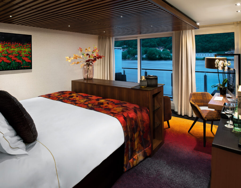 A river cruise cabin with full balcony open to the river scenery showing why an upgraded stateroom is worth it.