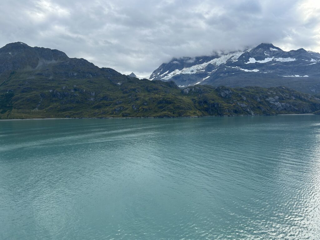 Alaska shore excursions guide: Tidewater glacier calving into the blue waters of Glacier Bay National Park in Alaska as seen from a cruise ship deck