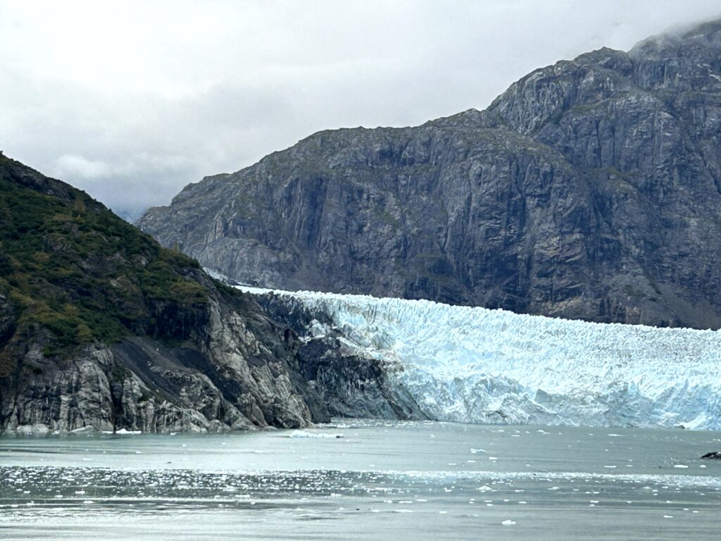 Margerie Glacier calving into Glacier Bay National Park Alaska viewed from the deck of a cruise ship on a scenic sailing day