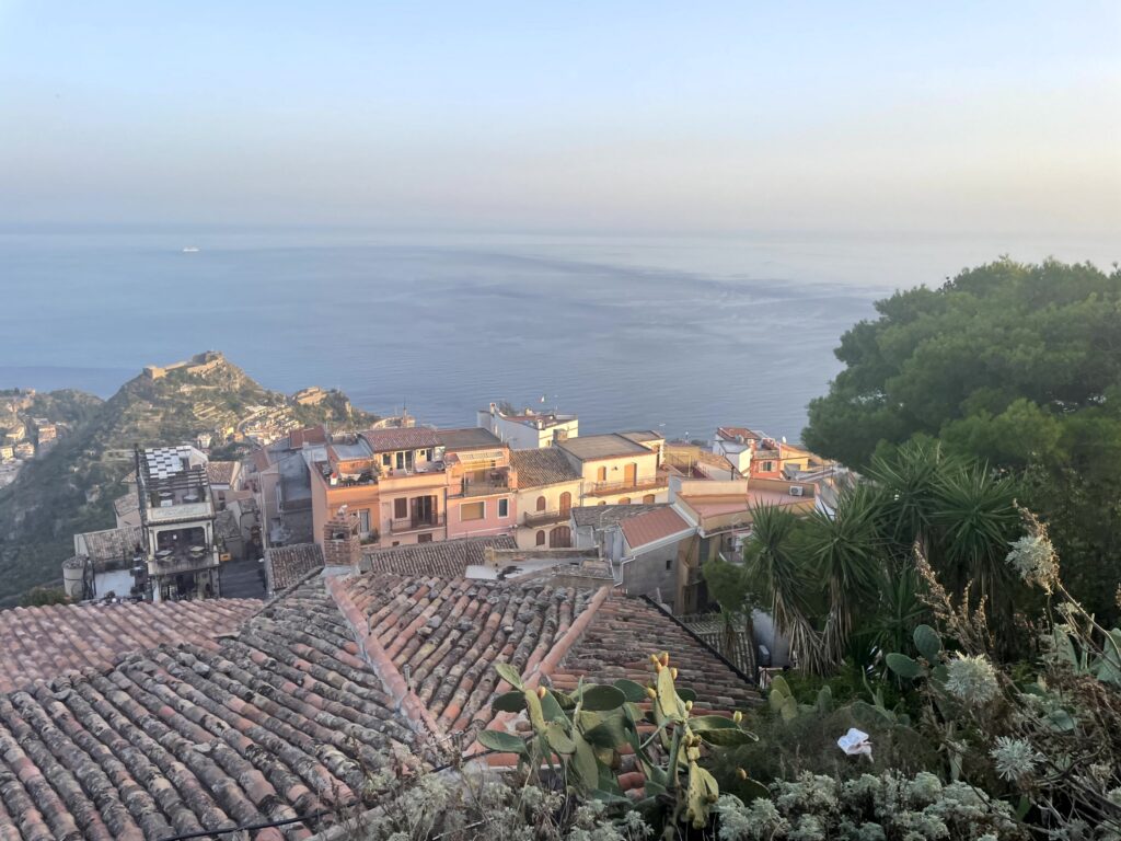Rooftops of Taormina and the Ionian Sea seen from Castelmola at dawn, a highlight of our Sicily road trip.