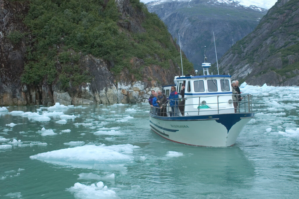 Opening (ship near a glacier): "A small expedition ship sailing near a glacier on an Alaska expedition cruise."